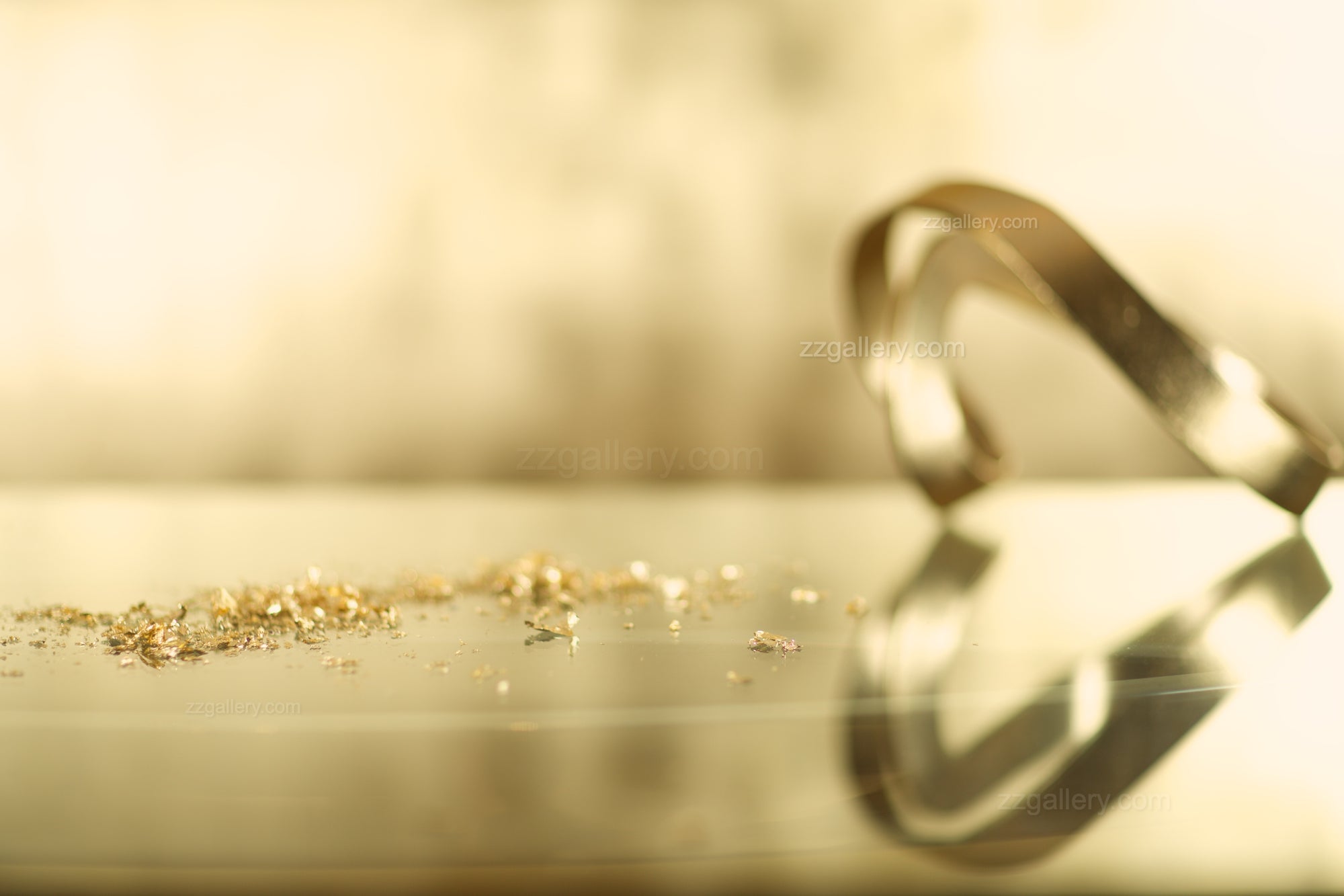 Golden metal ribbon with scattered gold dust photographed by Zack Zublena – sleek contemporary fine art object photography for collectors and interiors.