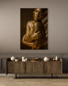 Elegant golden-painted nude woman with eyes closed and arms wrapped around her shoulders, captured in warm light against a neutral background. Contemporary fine art nude photography symbolizing serenity, self-love, and feminine strength — ideal for luxury interiors, spas, and collector wall art.