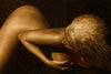 Golden-painted nude woman captured from above in a fluid curved pose, symbolizing sensual flow, inner grace, and feminine essence.
