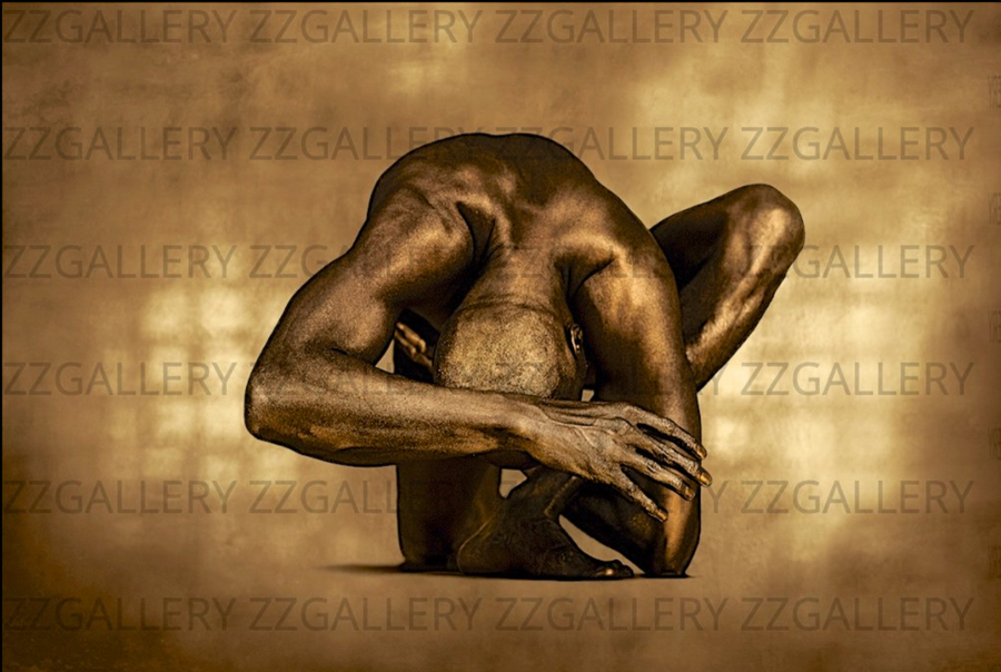 Golden nude male figure in sculptural fetal pose on neutral background