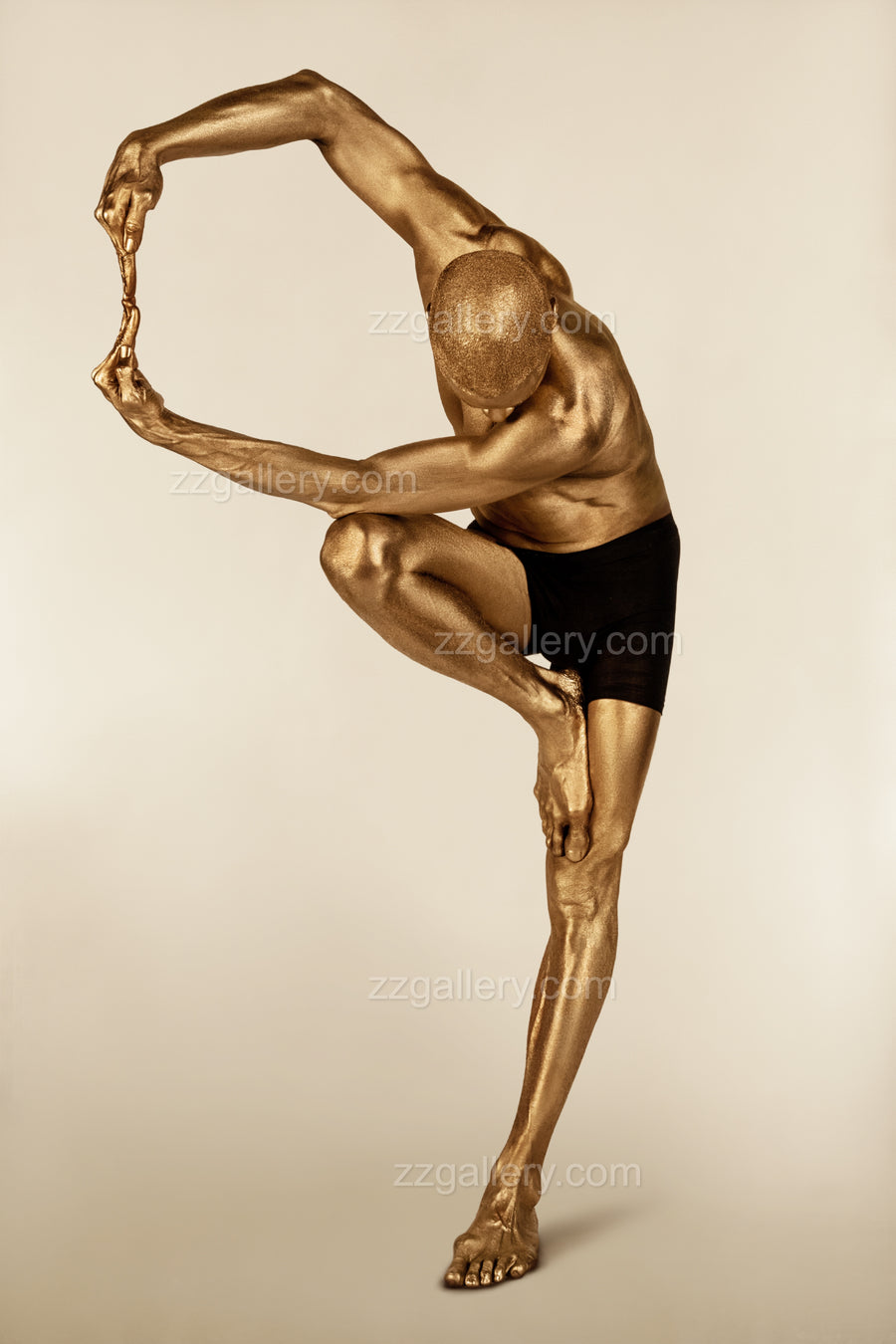 Golden-painted male figure in an advanced yoga pose, balancing on one leg with arms extended, fine art photography by Zack Zublena celebrating strength, flexibility, and inner focus.
