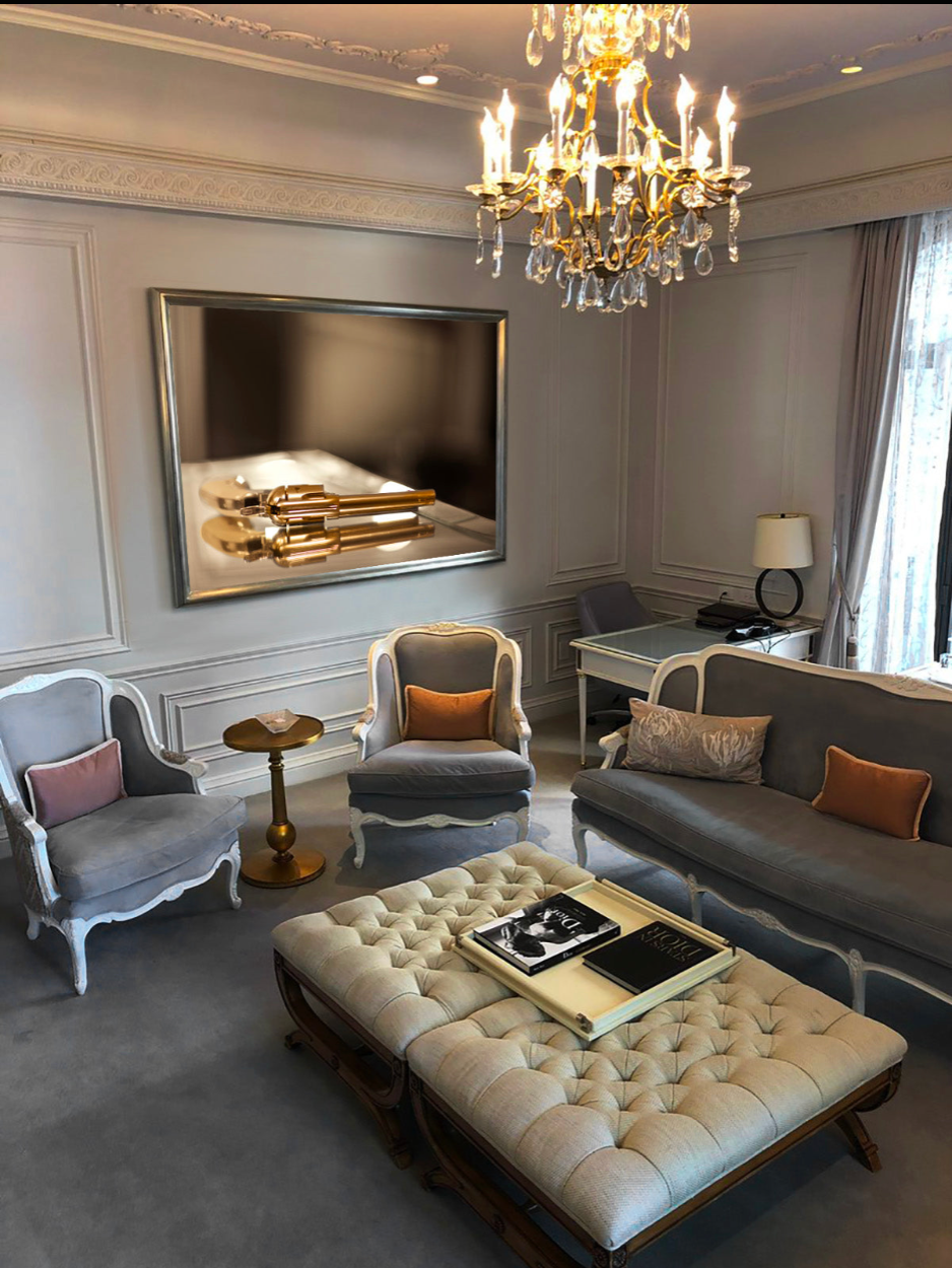 Golden revolver luxury wall art by Zack Zublena displayed in an elegant living room interior with chandelier and classic decor.