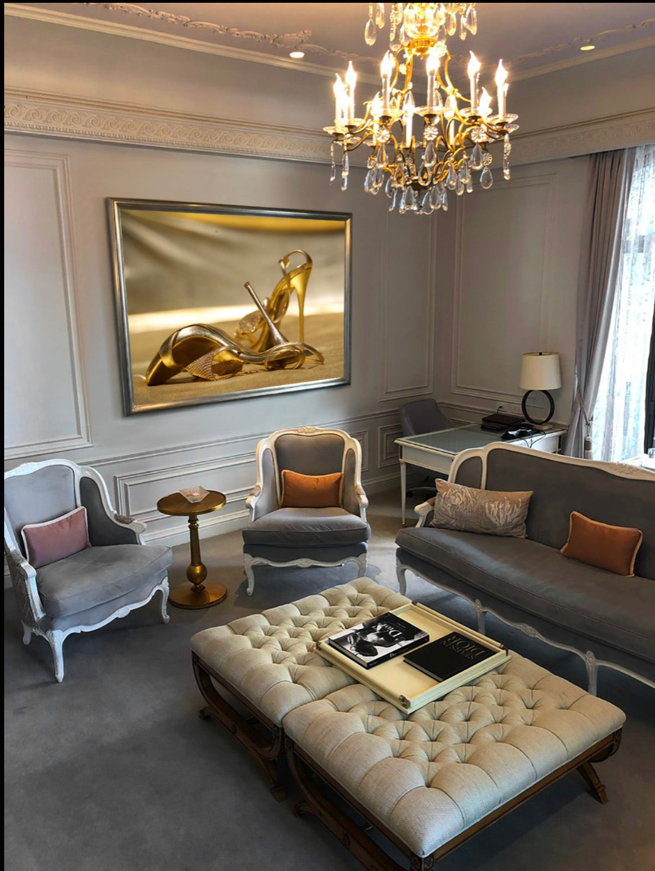 Golden ribbon and dust fine art photography by Zack Zublena displayed as luxury wall art in an elegant living room with chandelier and classic decor.