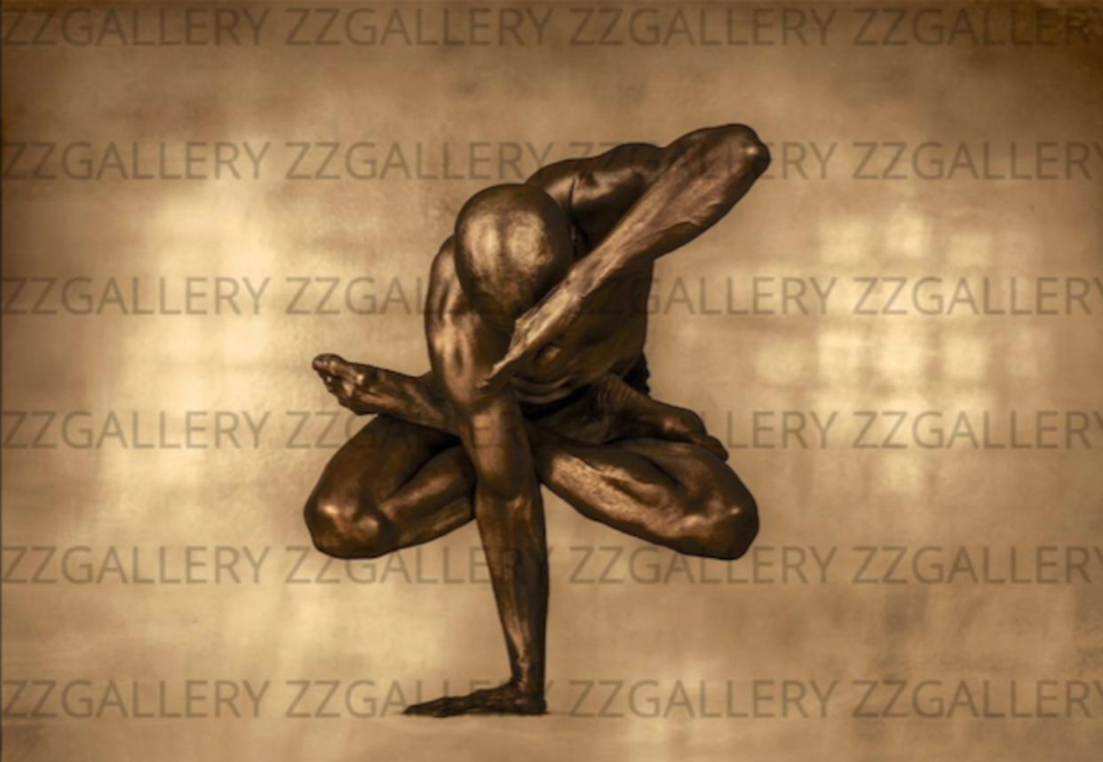 Golden-painted male figure in a suspended lotus yoga pose with arm covering face – artistic fine wall art photography