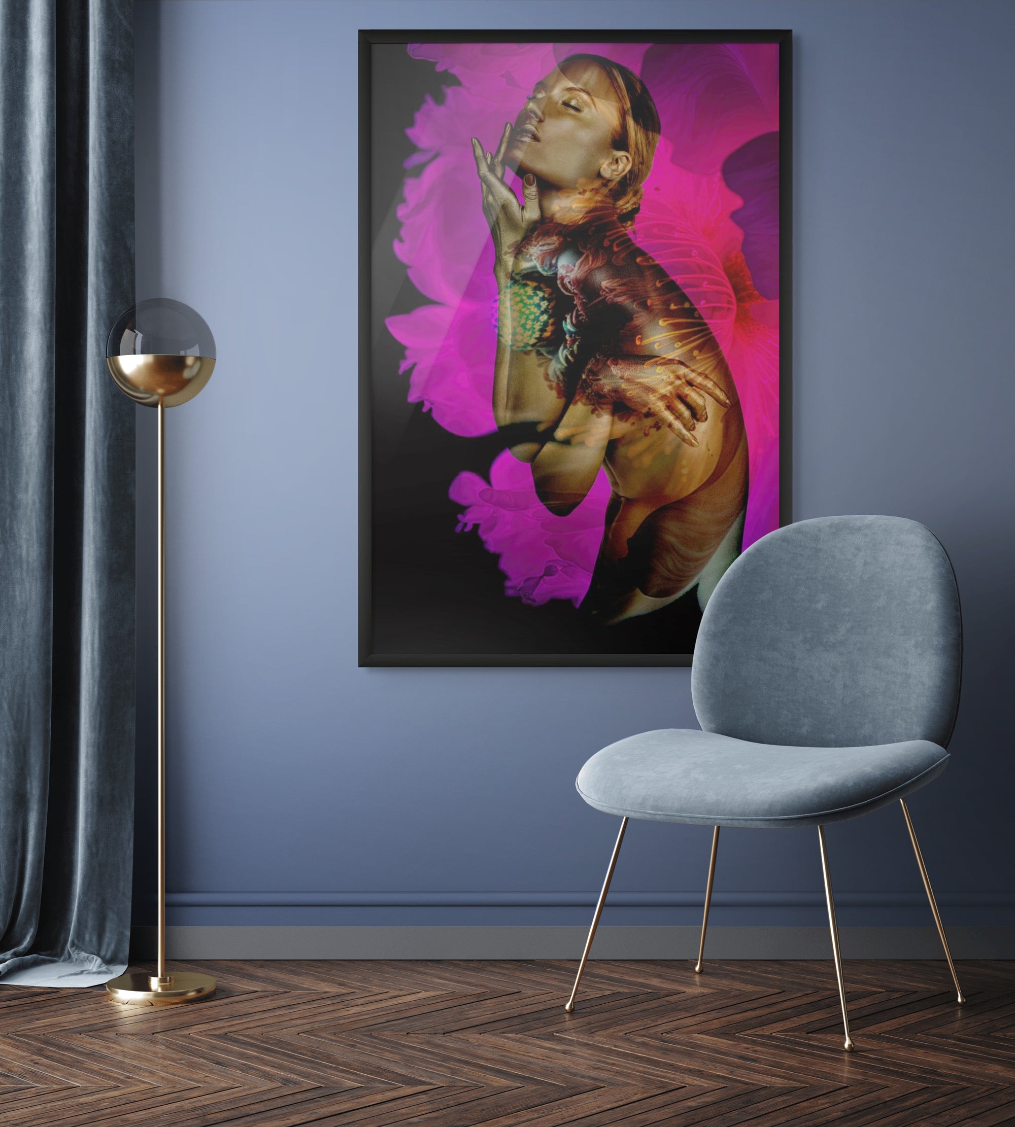 Framed surreal fine art photograph of a golden-painted figure with vivid pink floral details, displayed in a modern interior with blue walls and chair.