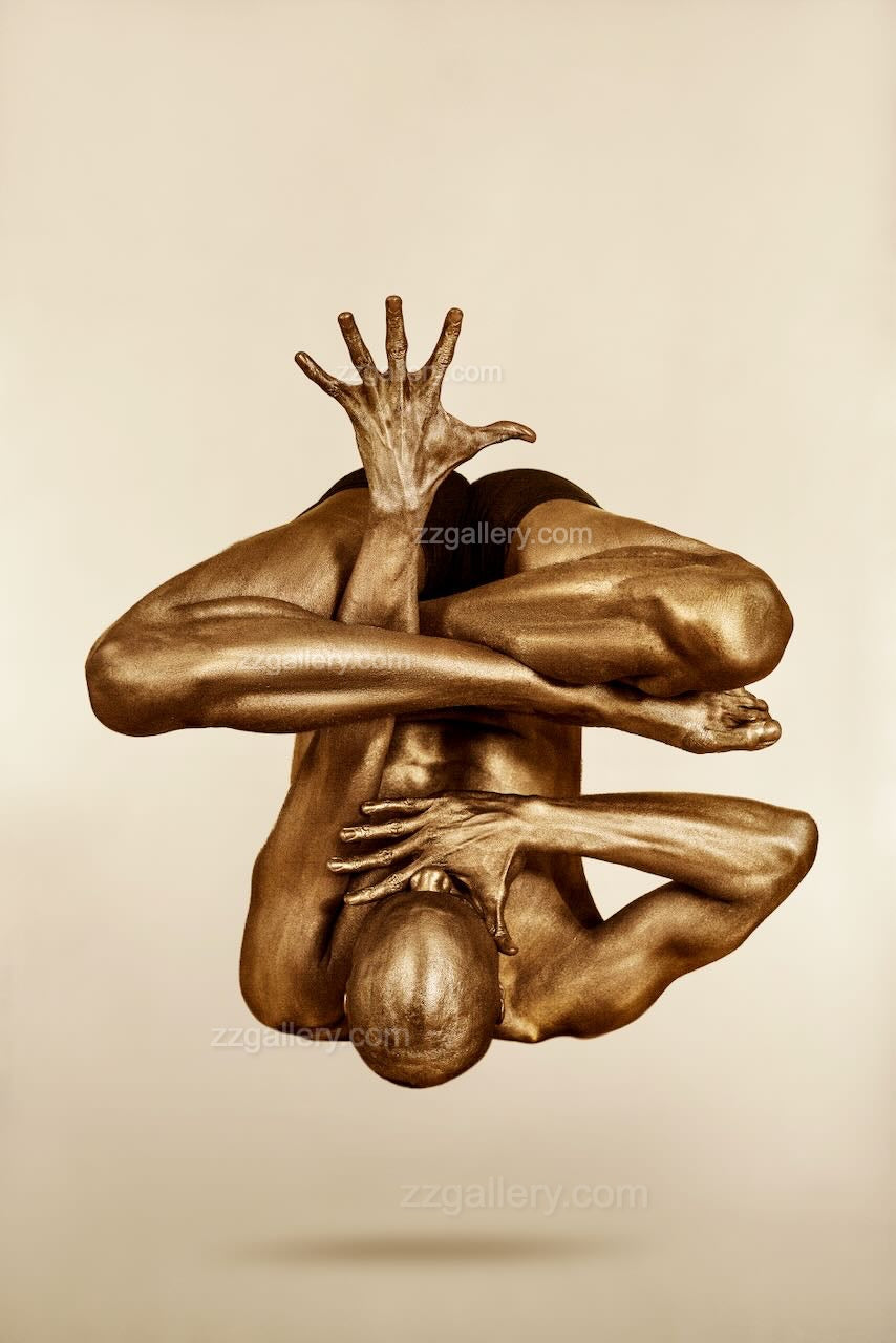 Fine art photograph of a gold-painted human figure suspended mid-air in a sculptural balance pose, contemporary wall art for luxury interiors, spas, and modern homes.