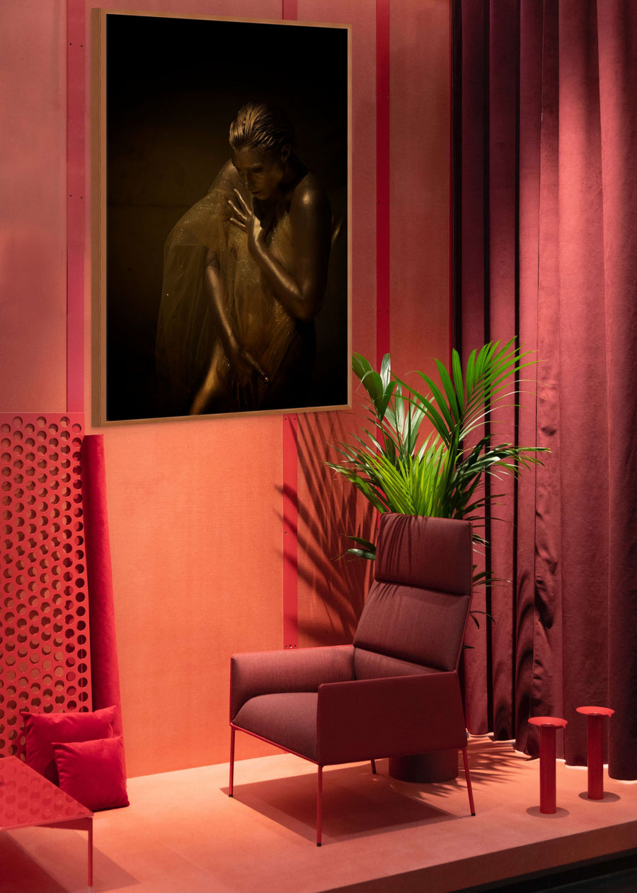 Golden veil fine art photography displayed in a luxury hotel-style interior, framed on a red-toned wall beside a modern chair and green plant.
