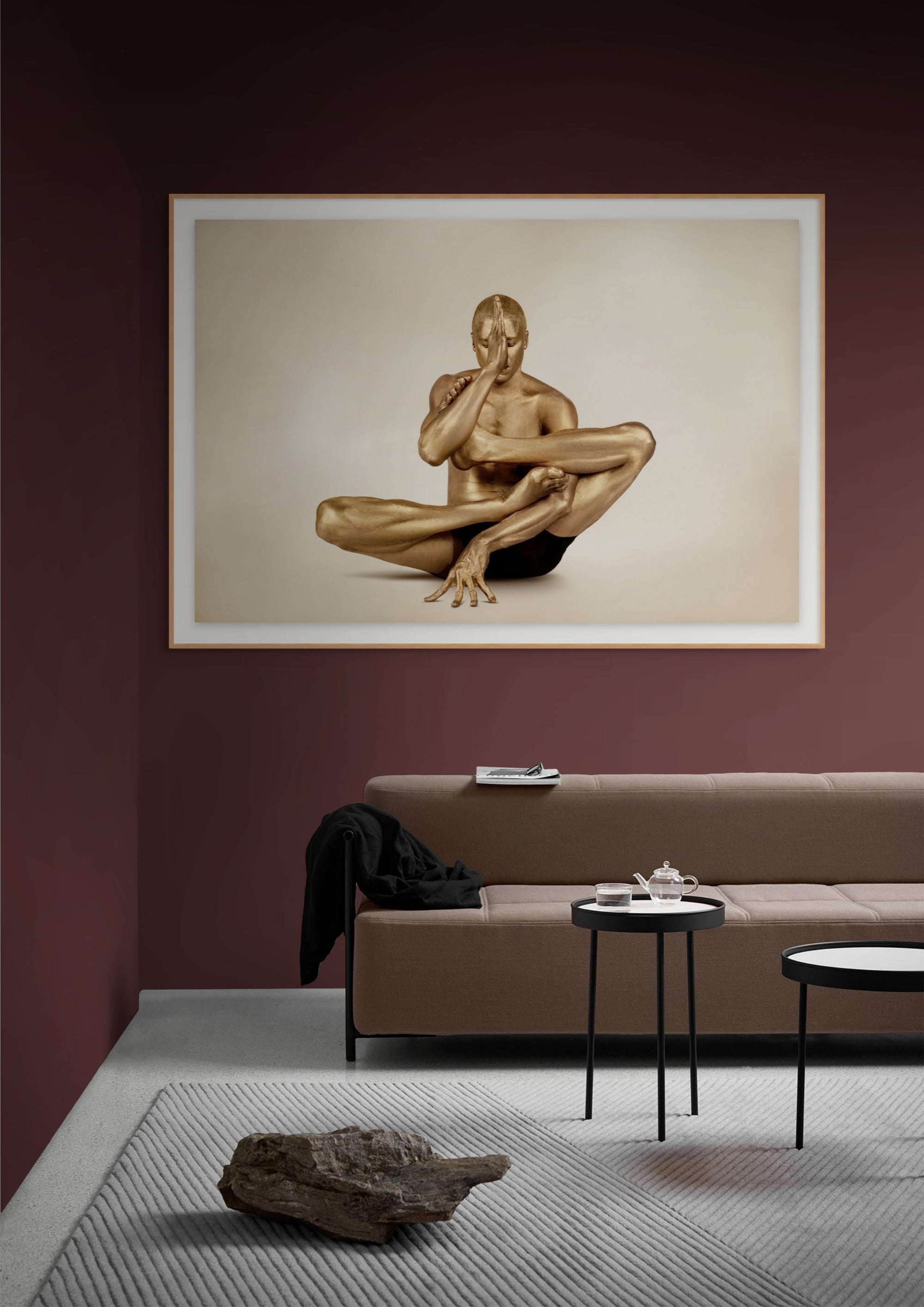Golden-painted male body in a complex seated yoga pose, covering one eye with his hand, captured in contemporary fine art photography by Zack Zublena.