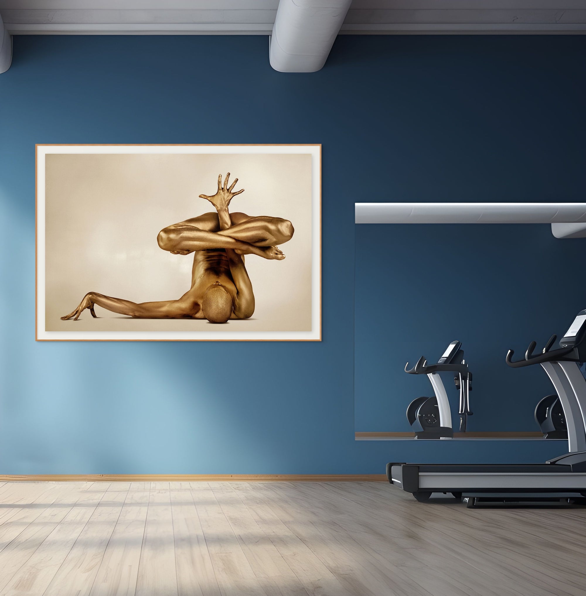 Golden painted body in advanced yoga hand balance pose, fine art wall decor by Zack Zublena, displayed in a modern gym with blue walls and treadmill.
