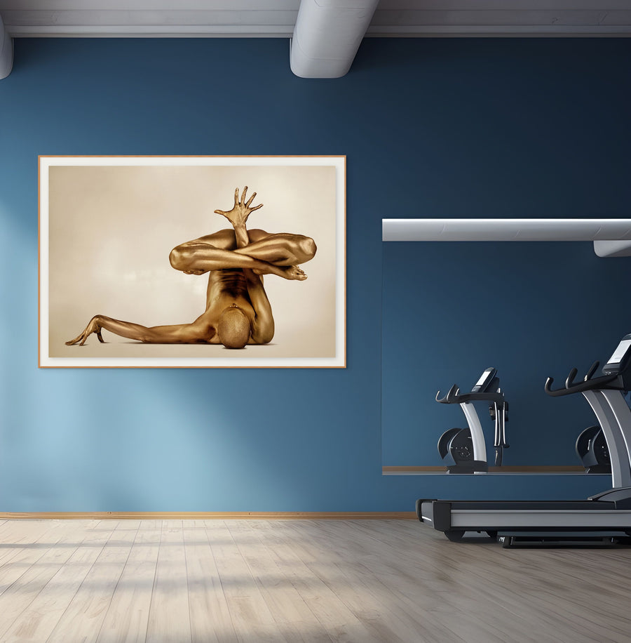 Golden painted body in advanced yoga hand balance pose, fine art wall decor by Zack Zublena, displayed in a modern gym with blue walls and treadmill.