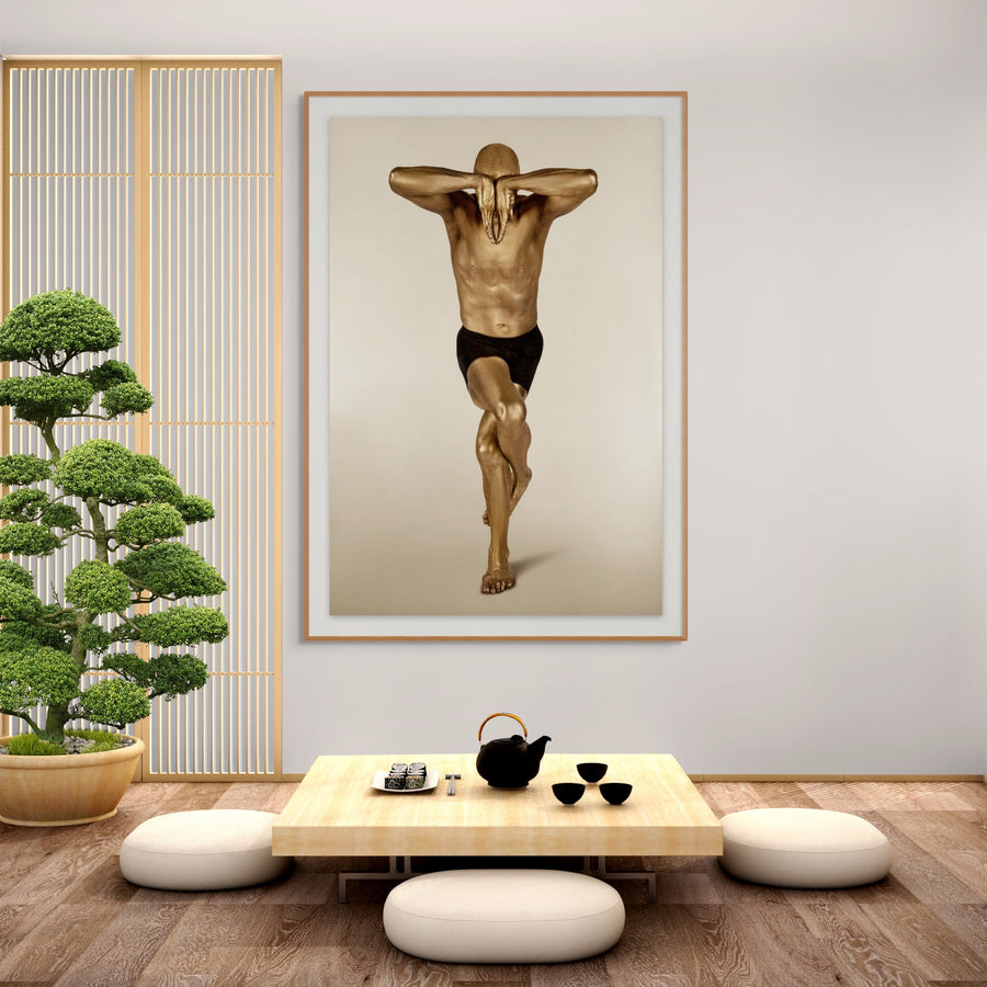 Golden-painted male figure in an elegant yoga balance pose, fine art photography displayed in a Japanese zen-style interior with bonsai and low tea table, perfect for wellness and meditation spaces.
