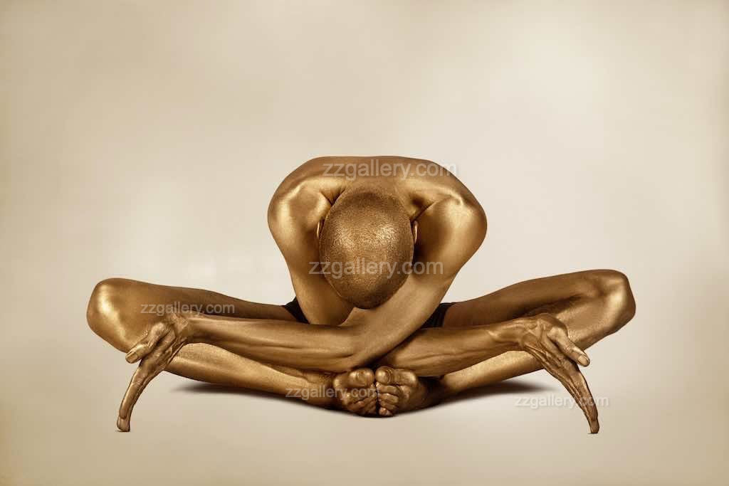 Golden-painted yogi in a deep forward bend pose with arms extended, embodying strength, serenity, and artistic elegance. Fine art wall décor by Zack Zublena.