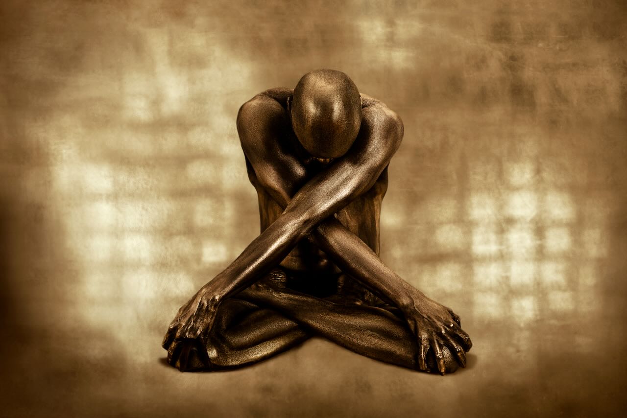 Golden-painted male yogi in lotus pose with arms crossed and head bowed – sacred meditation wall art photography