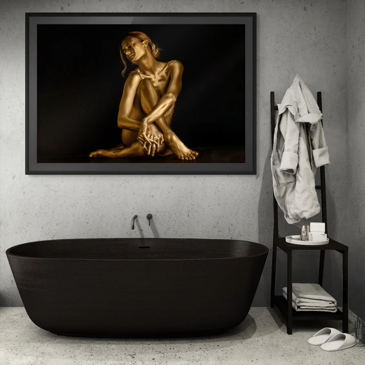 Gold-painted seated figure with clasped hands, framed fine art photograph “Moonlit Reverie III” by Zack Zublena, hanging above a black freestanding bathtub in a modern concrete-walled bathroom.