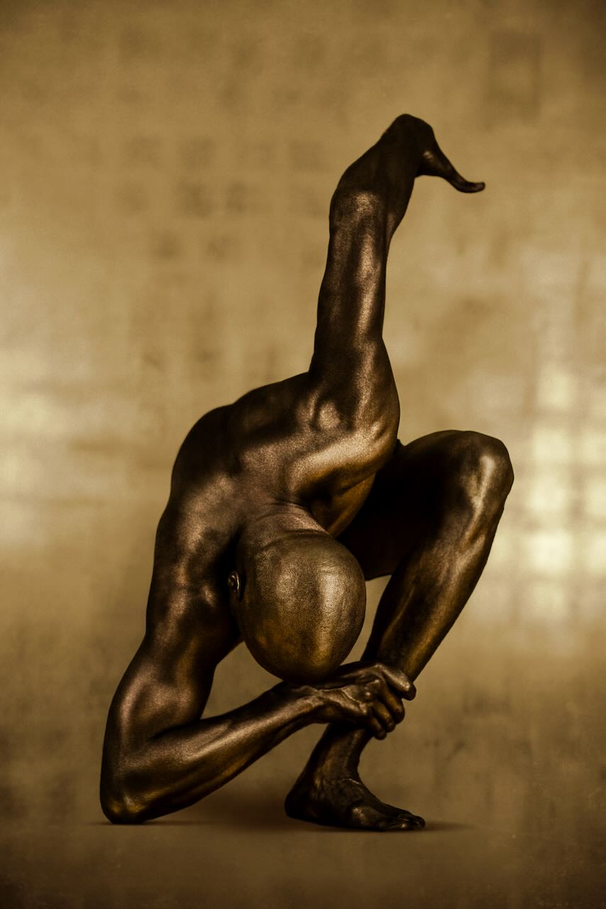 Golden male figure bowing in a sculptural yoga pose, arms folded in respect, contemporary fine art photography wall decor for meditation, spa, or luxury interiors.