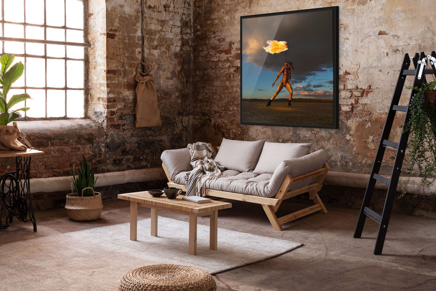 Interior view with framed fine art photograph Skyfall Flames III – Sacred Ignition by Zack Zublena, showing a golden-painted figure performing with real fire in El Mirage desert.