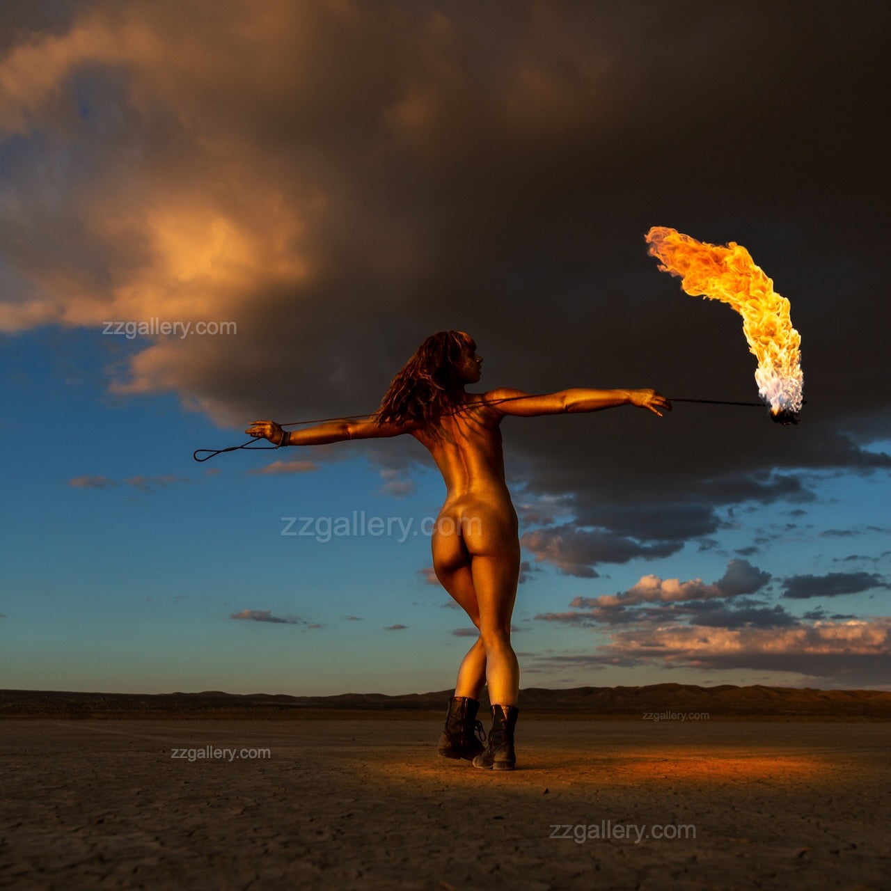 Golden-painted figure holding a blazing torch under dramatic desert sky at sunset, fine art photography from the Skyfall Flames collection.