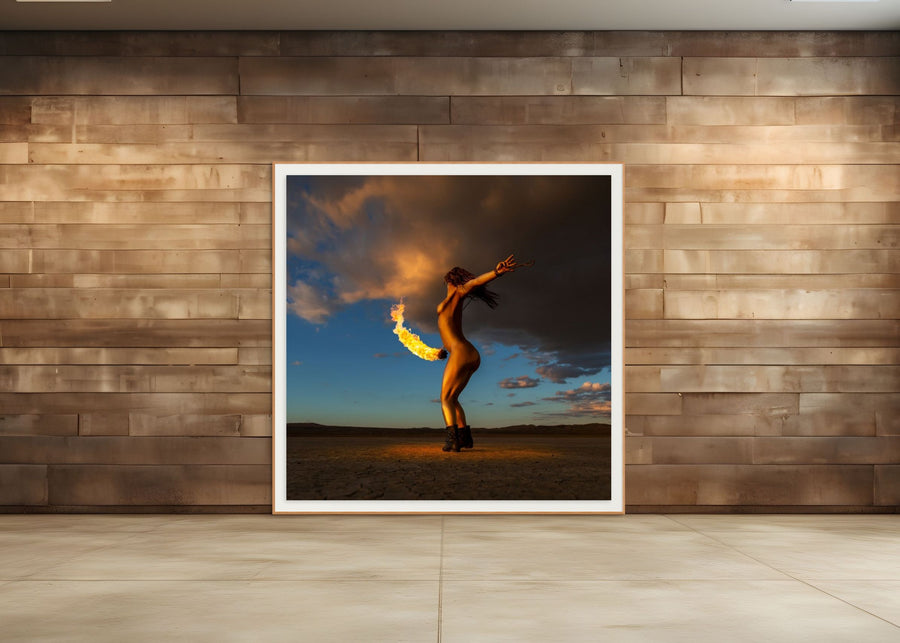 Framed fine art photograph of a gold-painted woman performing with fire in a desert at sunset, displayed on a modern wooden wall, from the Skyfall Flames VI – Phoenix Ascent series.