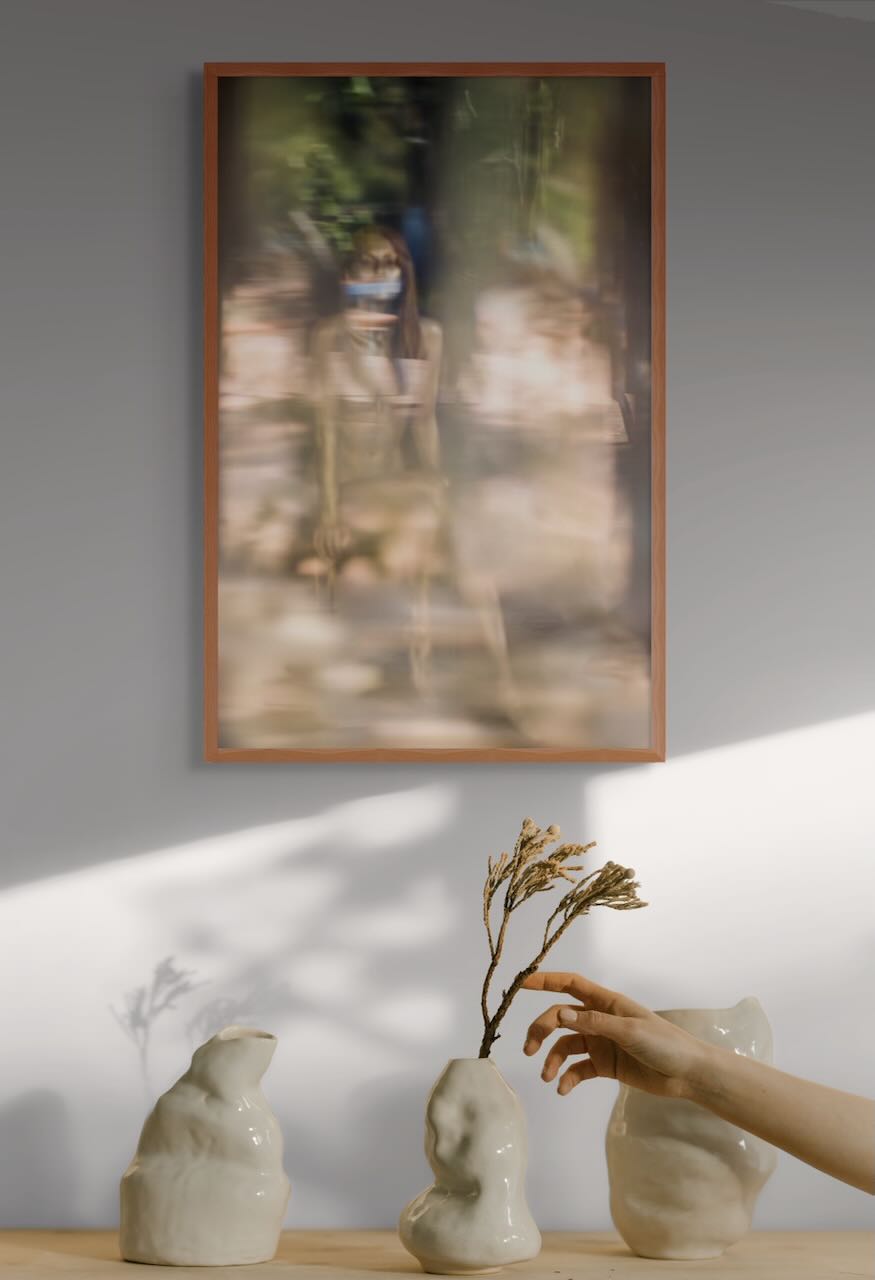 Framed Via Lactea golden reflection fine art print displayed above a minimalist table with ceramic sculptures and a hand holding dried flowers.