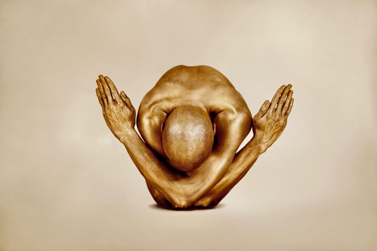 Victory Needs No Witness by Zack Zublena, a gold-painted figure in a sculptural pose against a warm beige background.
