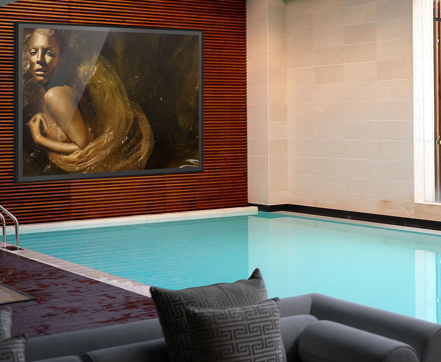 Golden Souls fine art photography print by Zack Zublena displayed in a luxury poolside interior, featuring a silhouette in shimmering gold tones draped in translucent fabric.
