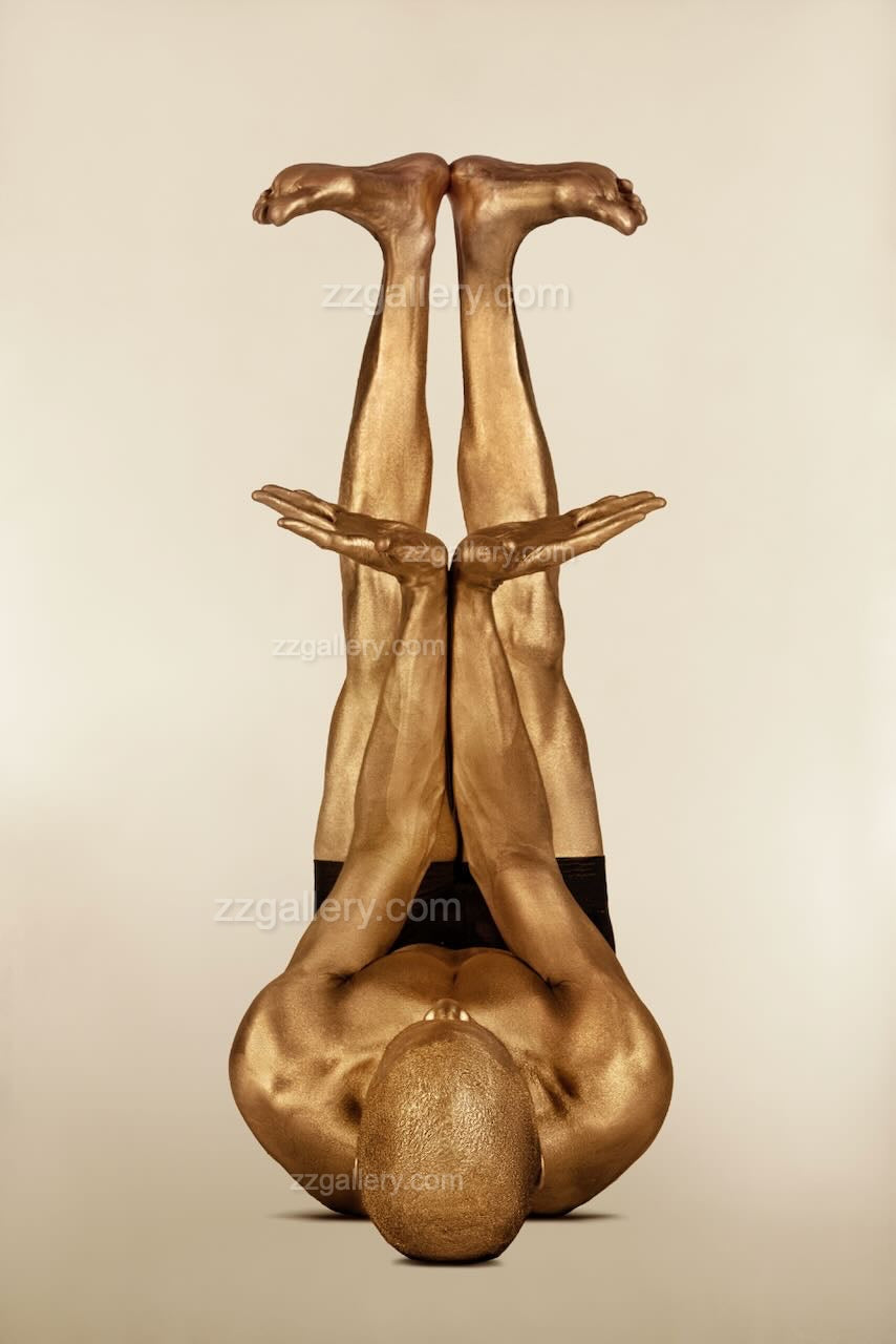 Golden-painted figure in inverted yoga pose with arms extended upward, fine art wall photography by Zack Zublena for yoga, wellness, and modern interiors.