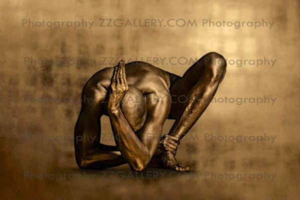 Golden-painted male figure in a sculptural crouching yoga pose, fine art photography highlighting strength, balance, and elegance. Luxury wall art for modern interiors, spas, and collectors.